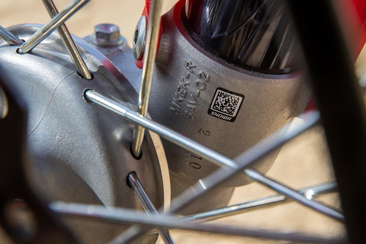 Welcome to the future. To ensure that the correct Showa parts are installed on every 49mm-equipped model, QR coding is utilized. Also pictured are the double-butted spokes Honda has used for quite some time. The 36 three-cross front and 32 two-cross rear wheelset is one of the lightest and strongest production designs.
