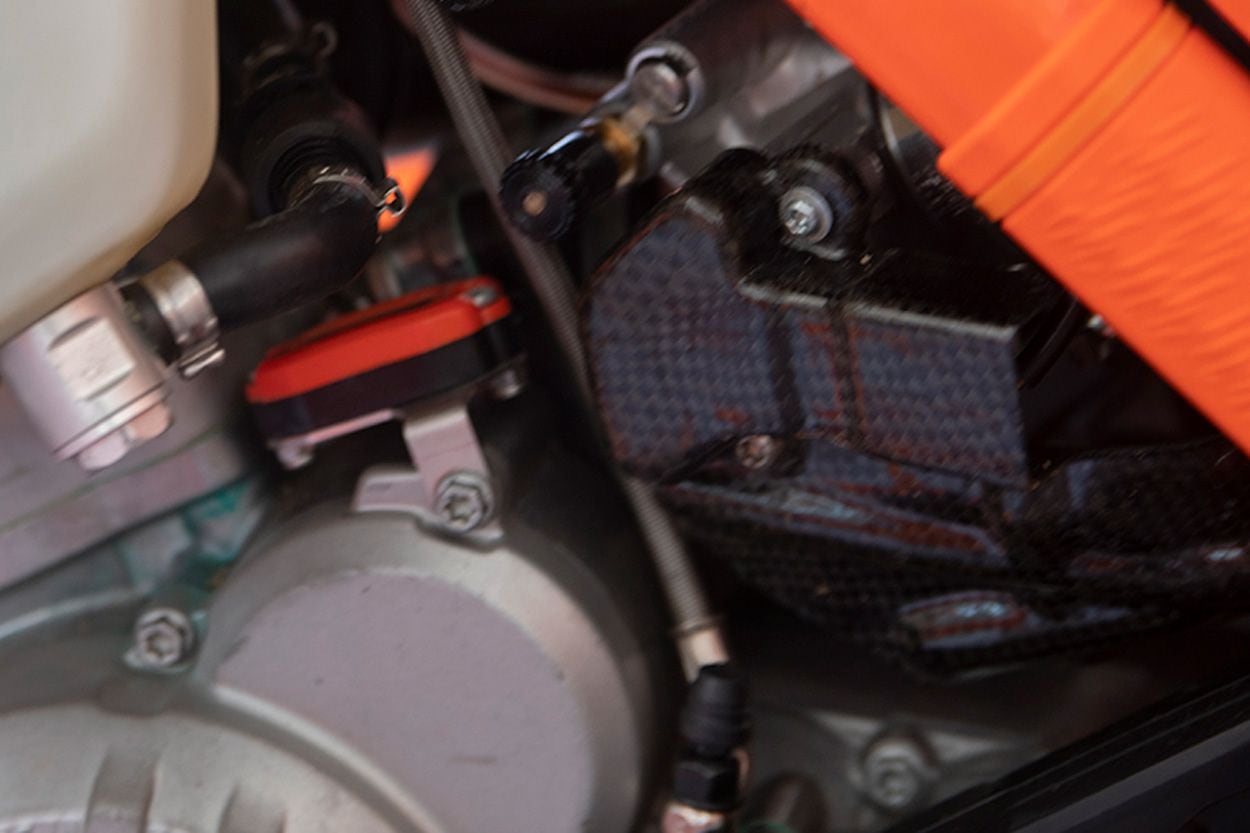 A carbon fiber guard protects the fuel line on the left side of the engine.