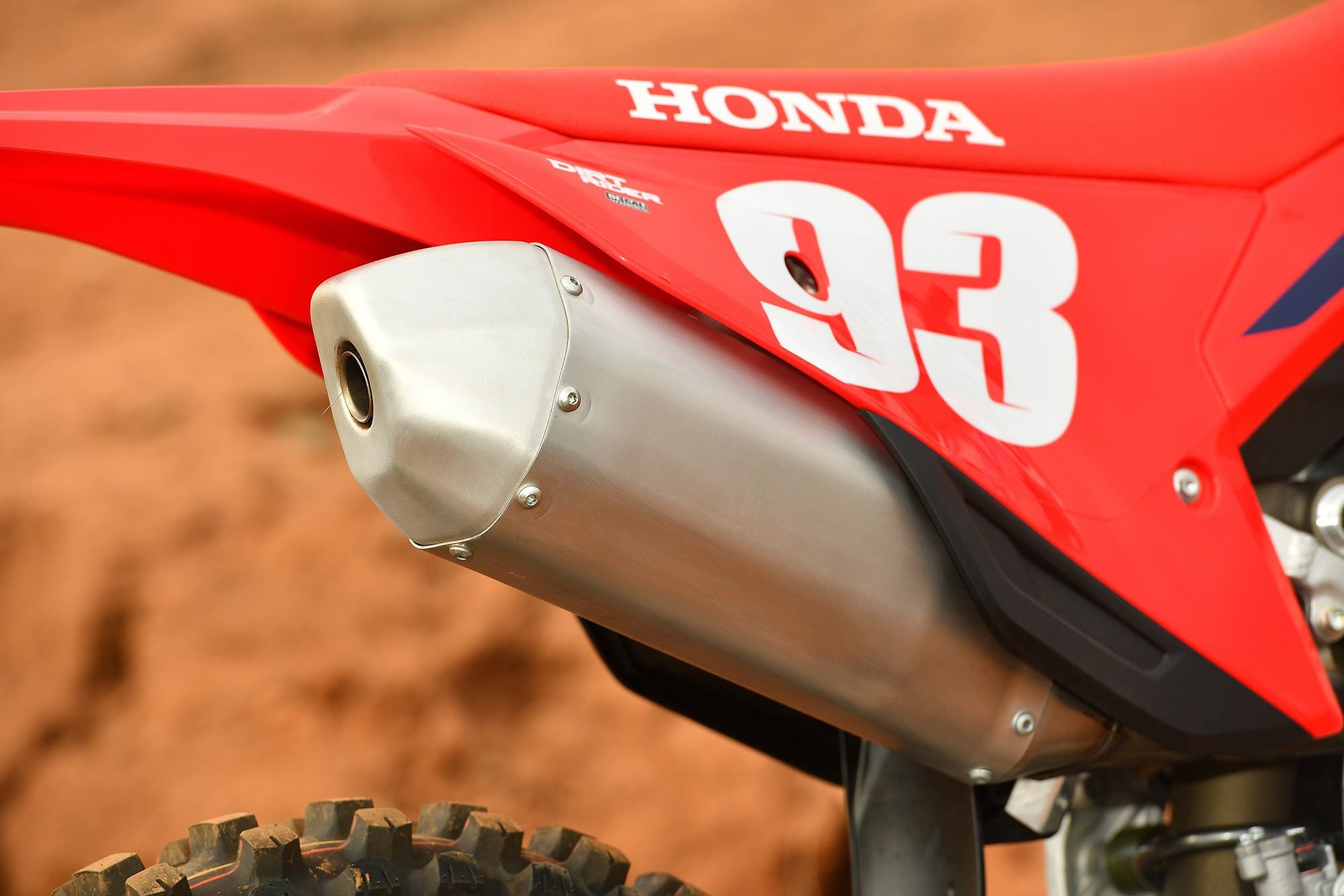 Close-up of the redesigned, more durable muffler and sleek red Honda bodywork.
