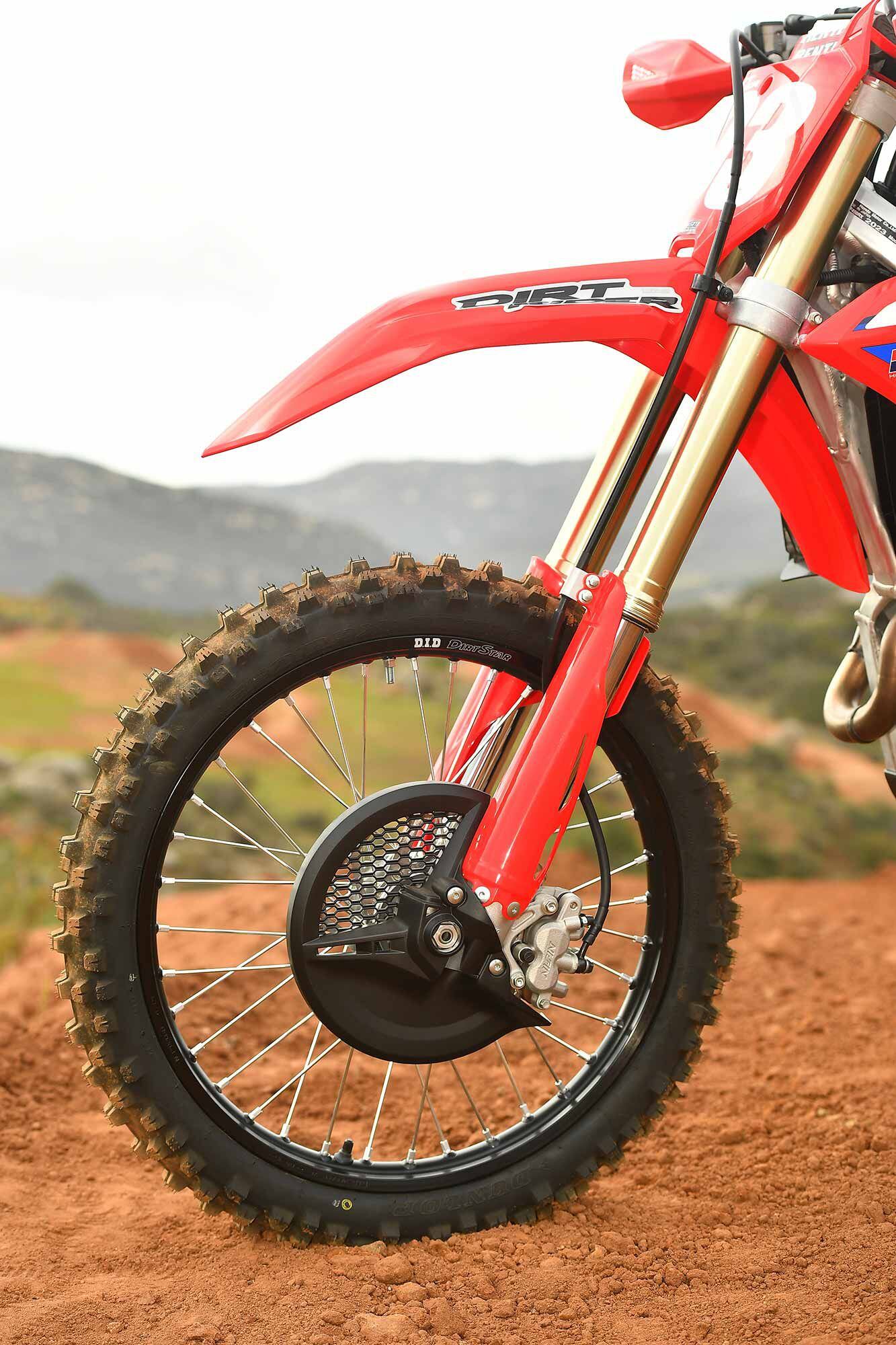 Proper front brake disc protection, D.I.D DirtStar rims, and Dunlop Geomax AT81 tires on the 2023 Honda CRF450RX. The 4.8 Nm fork springs and RX-specific settings make for a more compliant ride over the motocross-focused CRF450R.