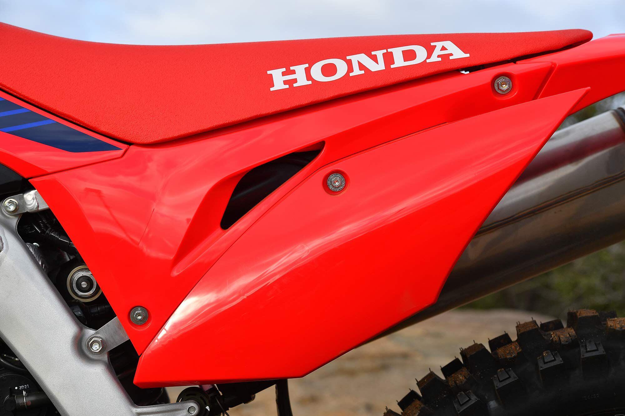 Check out these 10mm seat bolts in the traditional rear position on the CRF450X. While the CRF450R and CRF450RX seats slip on from front to back, the CRF450X still mounts from back to front. Interesting to note the blocked-off side panel vents. This keeps sounds down, but chokes up horsepower output.